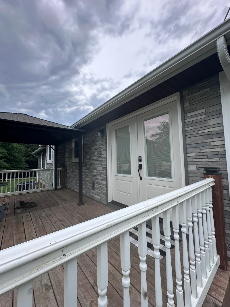 Finished home exterior with stone veneer and deck by Melos Construction